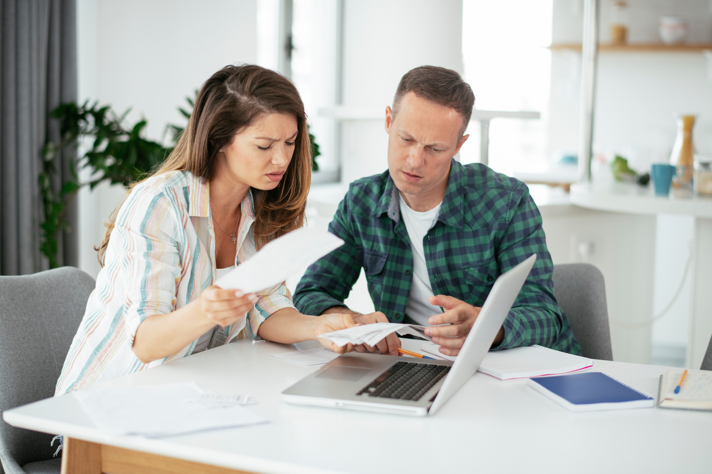 young couple in financial difficulty at home managing their bank accounts using a computer