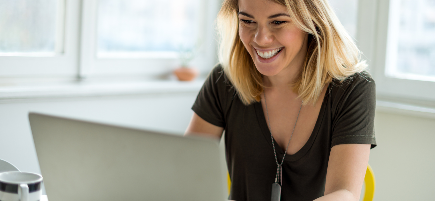 Femme souriante et radieuse qui travaille sur un ordinateur portable