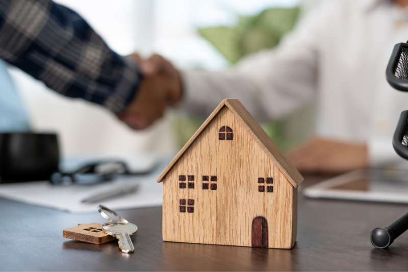 Hommes qui font une poignée de mains devant maison et argent